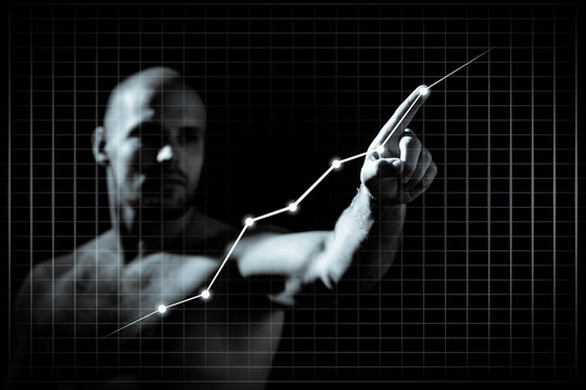 Young man in growth concept with a graph.Serious man drawing strategy on virtual screen on dlack isolated background
