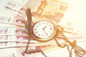 Money and clock on a chain on a white background. Time is money.