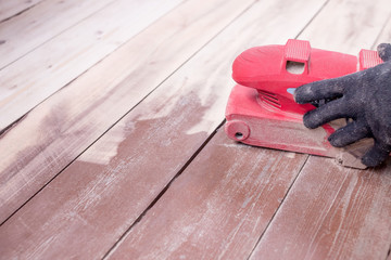 Wood floor polishing maintenance work by grinding machine. Men's hands with gloves make repairs at home. Grinding machine with a wooden floor.Copy space. restoration of the floor.