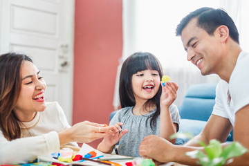 Girl daughter playing blocks toy over father and mother, happy family concept
