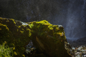 Wet from the spray of the waterfall stones with moss. Fresh mountain river and stone close up