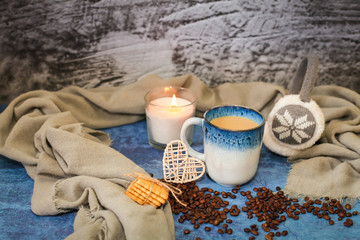 Autumn and winter background with candle, scarf, mug of cocoa, coffee or hot chocolate with scattered coffee beans