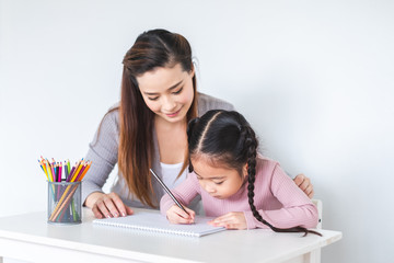 Asian girl kid and mother doing drawing with many colour pencils on white paper over white...