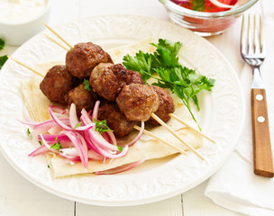 Lamb kebabs on skewers with onion and buttermilk sauce.