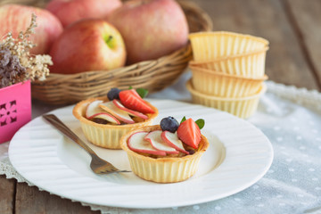 Homemade bakery apple caramel tart decorated with sliced apple strawberry and blueberry on white...