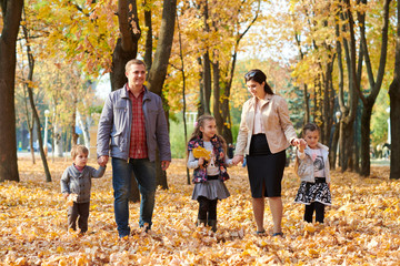 Naklejka na ściany i meble Happy family is in autumn city park. Children and parents. They posing, smiling, playing and having fun. Bright yellow trees.