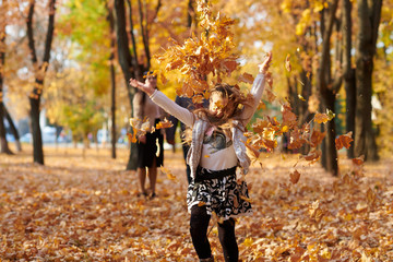 Happy family is in autumn city park. Children and parents running with leaves.. They posing, smiling, playing and having fun. Bright yellow trees.