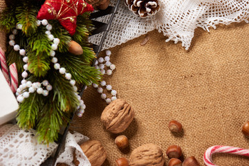Christmas decoration background, fir tree, textile, beads, gifts, old paper, nuts and other stuff on sackcloth. Empty space for text, new year theme.
