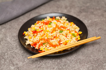 Chinese fried rice with vegetables, served on a plate with chopsticks. Selective focus