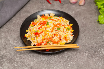 Chinese fried rice with vegetables, served on a plate with chopsticks. Selective focus