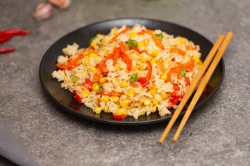Chinese fried rice with vegetables, served on a plate with chopsticks. Selective focus