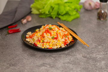 Chinese fried rice with vegetables, served on a plate with chopsticks. Selective focus