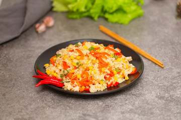 Chinese fried rice with vegetables, served on a plate with chopsticks. Selective focus