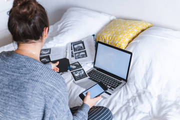 woman holding card with phone in hand. laptop with white screen. medical results on background