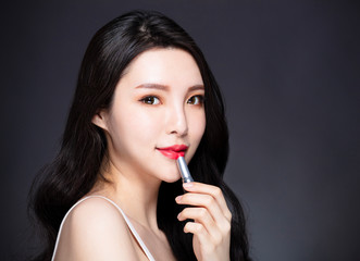 young beauty Painting lips with lipstick