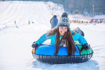 young smiling girl ride sleigh snow tubing hill winter activity