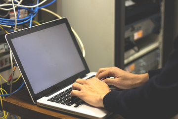 hands man using laptop to check servers in data center. system administrator working in data center.