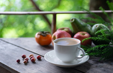 Coffee cup on wooden table with Coffee Cherries and fruits