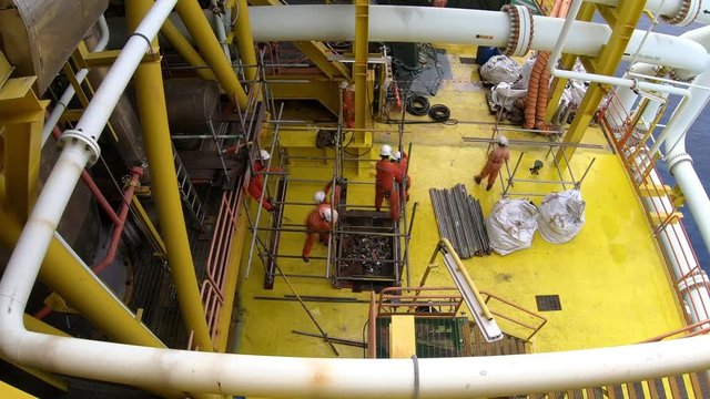 Top view of 4K time lapse offshore workers performing scaffolding erection for temporary materials storage on oil and gas platform.