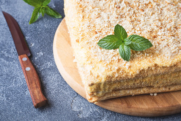 Layered cake with cream Napoleon millefeuille vanilla slice with mint on dark background.