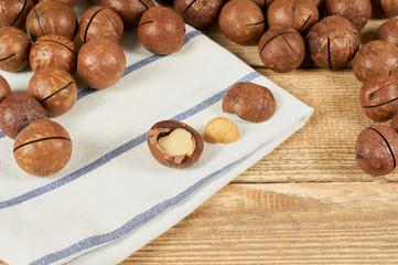 Macadamia nuts and white napkin on wooden table, close-up