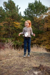 Redhead girl in a jump in the forest