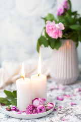 Cozy still life with candles and pink roses on a white table. Romantic home evening concept
