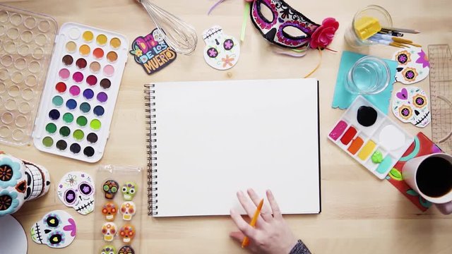 Step by step. Flat lay. Baker sketching a design of a cake for Dia de los Muertos holiday.