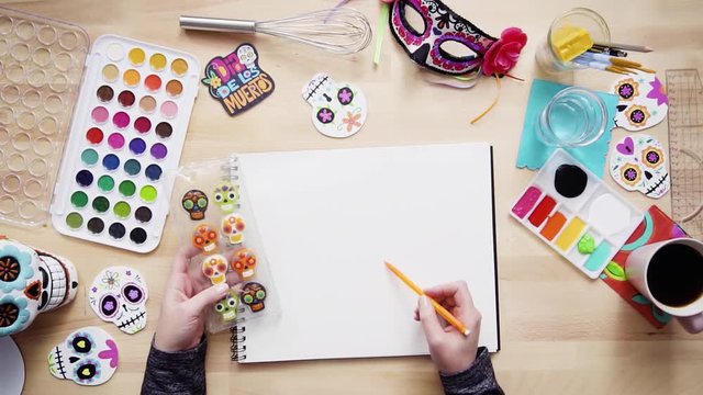 Step by step. Flat lay. Baker sketching a design of a cake for Dia de los Muertos holiday.