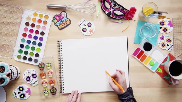 Step by step. Flat lay. Baker sketching a design of a cake for Dia de los Muertos holiday.