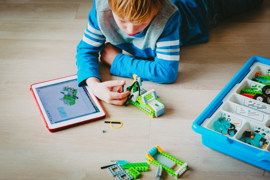 little boy building robot and programming it with touch pad