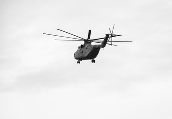 a large military helicopter hovers in the sky. A camouflaged helicopter flies at high speed.