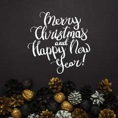 Pine cones and nuts painted in golden, black, white colors on a black background. Added text Happy New Year and Merry Christmas. Flat lay, top view