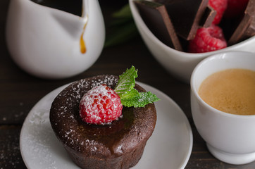 Chocolate fondant with raspberryand coffee cup. Molten chocolate cake with  powdered sugar background.
