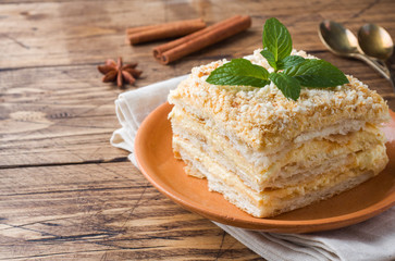 Layered cake with cream Napoleon millefeuille vanilla slice with mint on wooden background. - obrazy, fototapety, plakaty