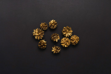 Pine cones colored in gold color on a black background. Minimalism. Concept of Happy New Year and Merry Christmas. Flat lay, top view