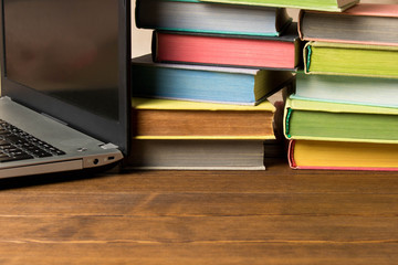 Books and laptop on wooden table. The concept of learning from books or from the Internet
