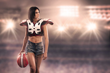A sportswoman posing with american football equipment at the stadium.