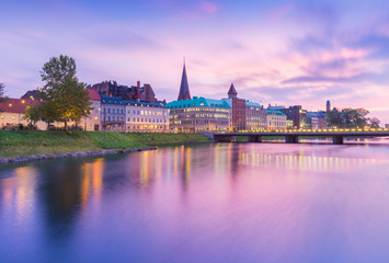 Naklejka premium Beautiful sunset in Malmo, Sweden. Picturesque view of an old European city in the evening. Skyline reflected in the water. Long exposure photography