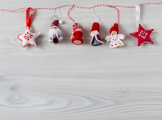 handmade felt toys hung on a light wooden background on a rope: Snow Maiden, Santa Claus, stars and free space for text