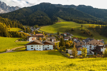 Fototapeta na wymiar a village in the middle of a green valley, Val Di Funes