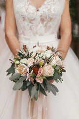 Obraz na płótnie Canvas Gorgeous beautiful bride holding stylish wedding bouquet on background of modern dress. Wedding decorations