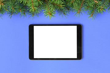 Tablet with blank screen on the purple pastel color background. Top view with christmas decor