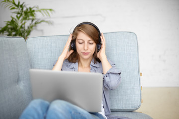 Modern technology, fun and relaxation concept. Pretty woman spending nice time indoors, listening...