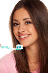 young woman brushing her teeth with tooth brush on white background