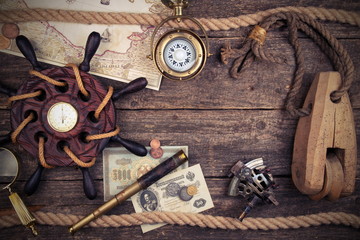 Fototapeta na wymiar Old ship steering wheel,compass,coins,monocle,loupe, sextants,rope,candle and pirate map. Travel and marine engraving background. Treasure hood concept. Vintage style.