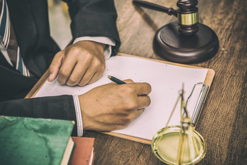 tribunal Attorney lawyer working with documents and wooden gavel on tabel in courtroom.