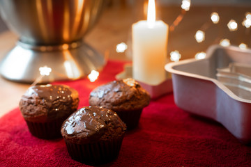 Table composition with chocolate muffins, candle and kitchen tools.