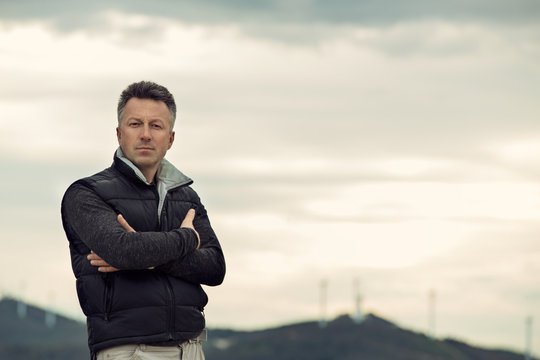 Handsome man. Outdoor male portrait over landscape with wind turbines. Image toned.