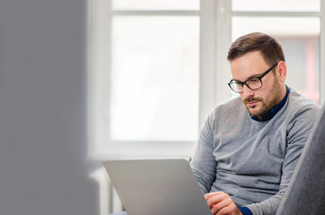 Young man with glasses working on a laptop from home